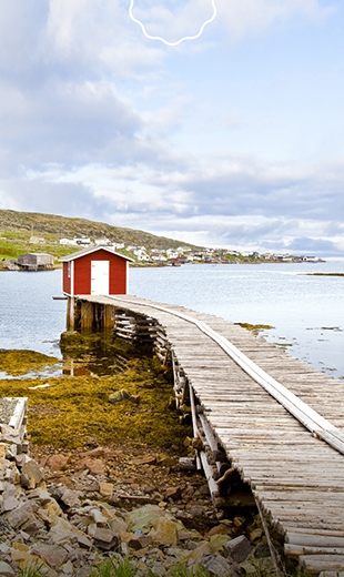 A wooden wharf leads out to a red fishing stage in Fogo.