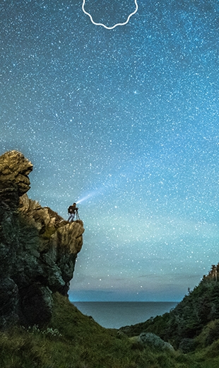 A traveller with a telescope looks up to the starry sky in Trout River.