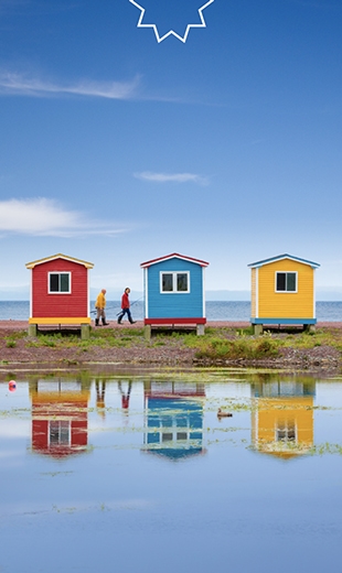 Two locals walk behind three colourful fishing stages in Cavendish.