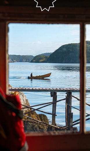 A person navigating a boat can be seen through a shed window in Collins Cove