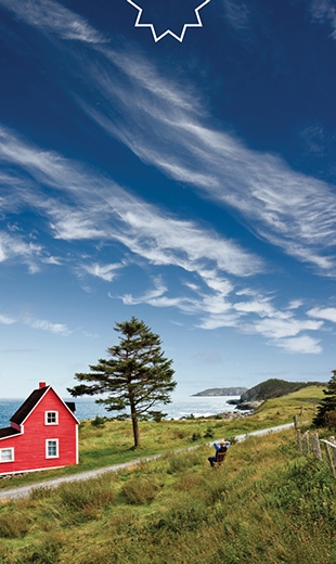 A person is resting in a chair next to a big red house.